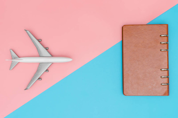 Toy plane and leather notebook on pink and blue copy space - Foto, afbeelding