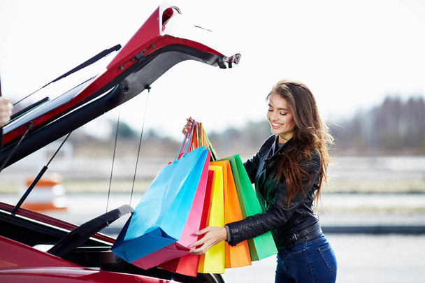woman putting colorful bags into car - Photo, Image