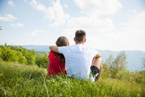 active couple rests on a mountain peak looking on a mountain lan - Foto, immagini