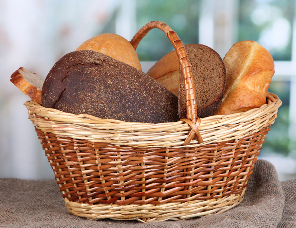Fresh bread in basket on wooden table on window background - Photo, Image