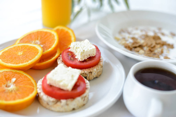 Petit déjeuner matinal avec pains, tomates et jus d'orange
 - Photo, image