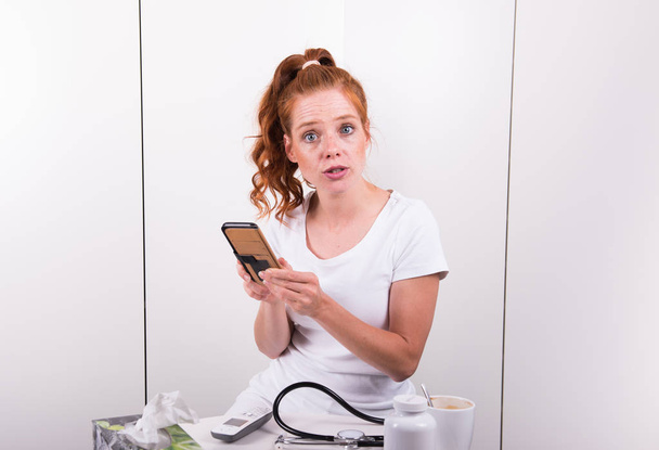 Young red-haired female doctor looks worried at diagnosis result - Photo, Image