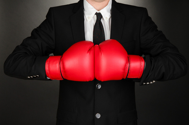 Businessman in boxing gloves on grey background - Фото, изображение
