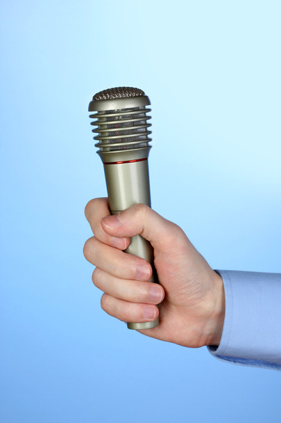 Male hand with microphone on blue background - Zdjęcie, obraz