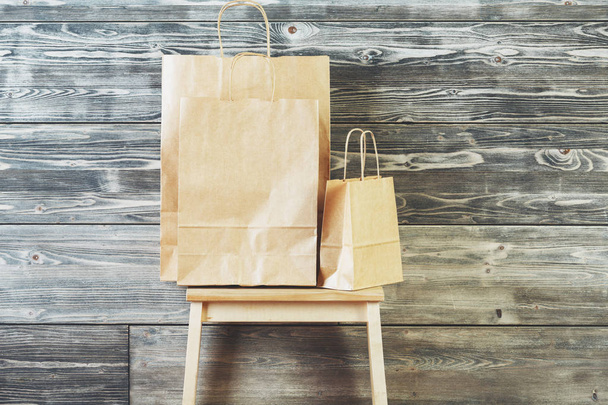 Empty brown paper shopping bags placed on step ladder. Wooden plank wall background. Advertising concept. Mock up  - Photo, image