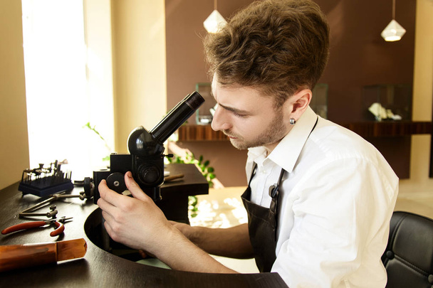 A jeweler man adjusts the microscope before starting work - Zdjęcie, obraz