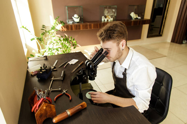 Ékszerész megvizsgálja a gyűrű egy mikroszkópot - Fotó, kép