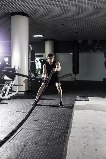 Hombre musculoso atractivo haciendo ejercicio con cuerdas pesadas. Foto de un hombre guapo en ropa deportiva. Crossfit
 - Foto, Imagen