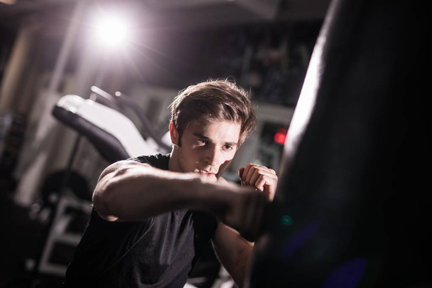 Portrait of boxer trying to kicking punching bag in gym while training. Training - Foto, Bild