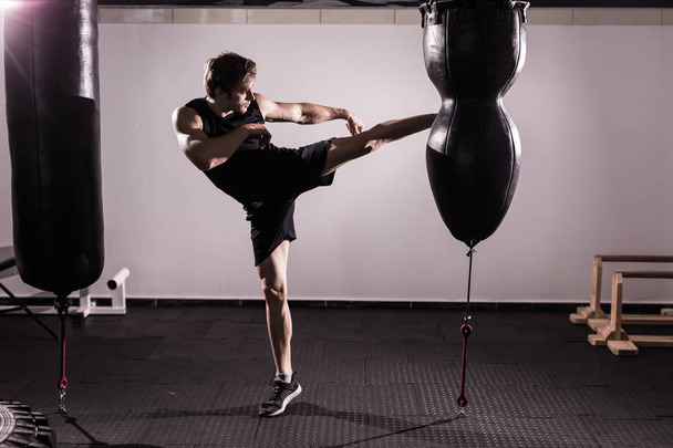 Boxeador con saco de boxeo en acción - Un hombre con un tatuaje en guantes de boxeo rojos - Boxeo
 - Foto, Imagen
