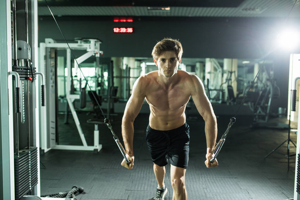 Muscular man lifting weights in fitness gym center - Фото, зображення