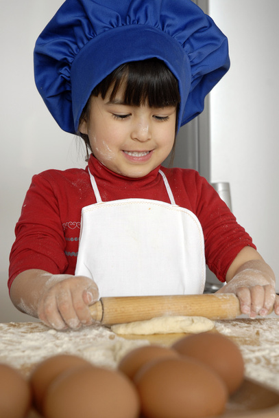 Little girl cooking a pizza in a kitchen.Little kid in a kitchen.Little girl cooking a pizza in a kitchen.Little kid in a kitchen. - Foto, Imagen
