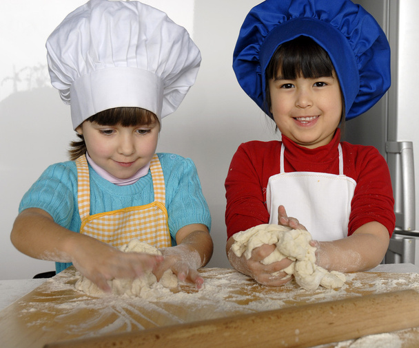 Two Little girls cooking a pizza in a kitchen.Little kid in a kitchen together. - 写真・画像