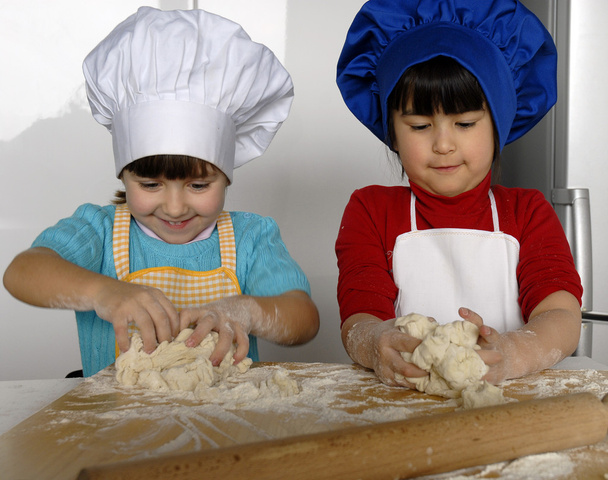 Two Little girls cooking a pizza in a kitchen.Little kid in a kitchen together. - Valokuva, kuva