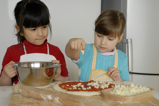 Two Little girls cooking a pizza in a kitchen.Little kid in a kitchen together. - Фото, зображення