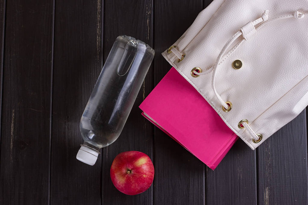 Білий шкіряний рюкзак, рожева книга, пляшка води
 - Фото, зображення