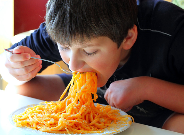Hauska poika syö spagettia.
. - Valokuva, kuva