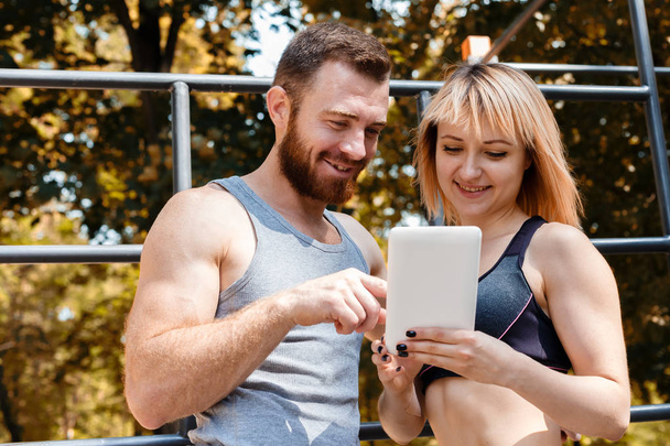 Young athletic woman and bearded man browsing the internet on ta - 写真・画像