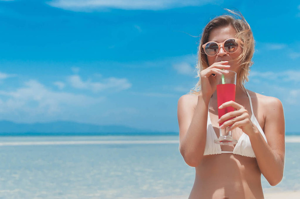 Girl in bikini drink juice through a straw. - Zdjęcie, obraz