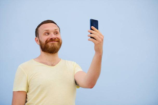 мужчина делает лица в смешном и юмористическом телефоне, показывает язык, рекламную компанию
 - Фото, изображение