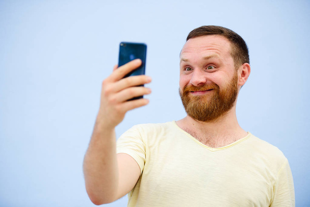 homem faz rostos em um telefone engraçado e bem-humorado mostra uma língua, uma empresa de publicidade
 - Foto, Imagem