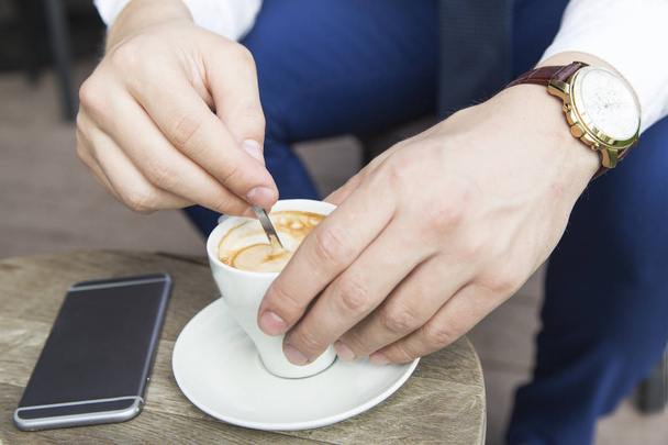 manos de hombre de negocios con taza de café y teléfono
 - Foto, Imagen