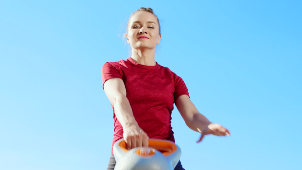 athletic young blond woman doing different exercises with weights, dumbbells, lunges, squats. Lake, river, blue sky and forest in the background, summer sunny day. close-up - Πλάνα, βίντεο