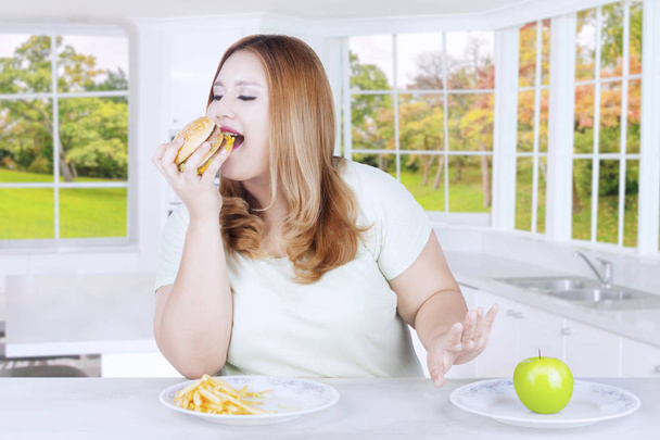 若いブロンドの女性がハンバーガーを食べる - 写真・画像