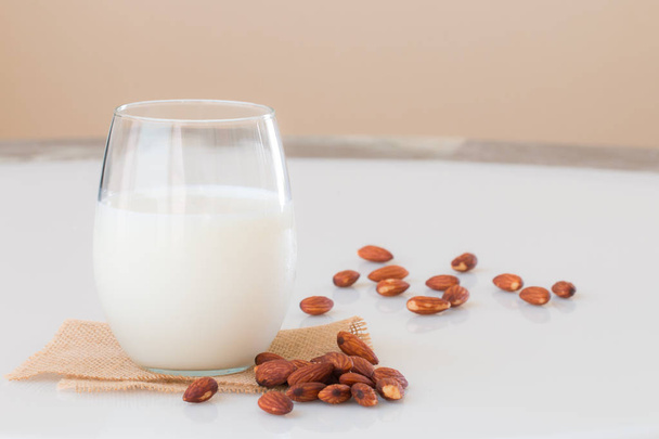 Amandel melk in een glas met amandel zaden op marmeren tafel.  - Foto, afbeelding