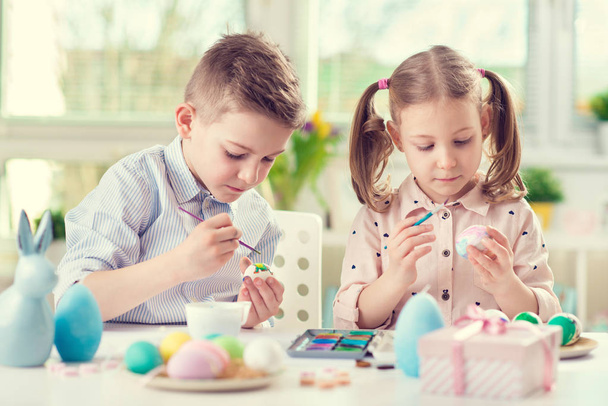 Two happy children having fun during painting eggs for easter in - Zdjęcie, obraz