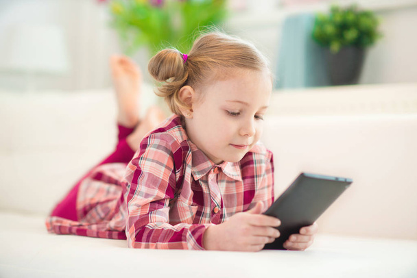 Pretty little child girl  using a digital tablet, looking and sm - Photo, image