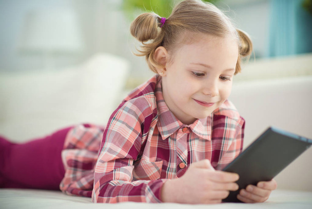 Pretty little child girl  using a digital tablet, looking and sm - Fotoğraf, Görsel