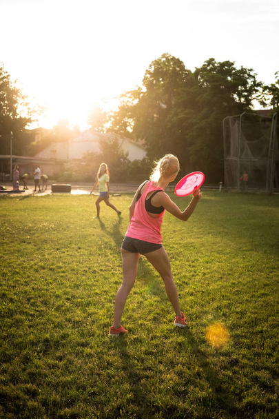 Two young and beautiful women playing frisbee in the park - Fotoğraf, Görsel