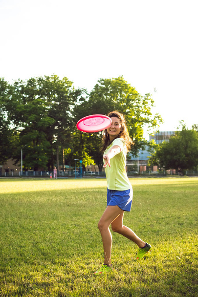 Young and beautiful woman playing frisbee in the park - Foto, Imagen