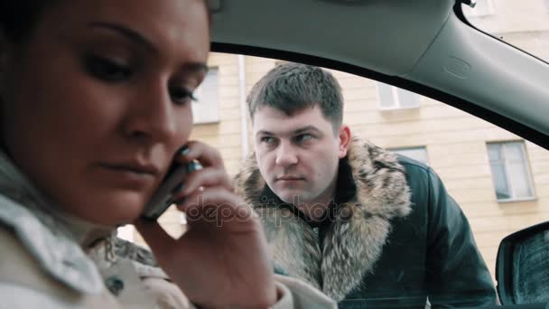 Gangster man in leren jas dwingt vrouw zitten in de auto om venster te openen - Video