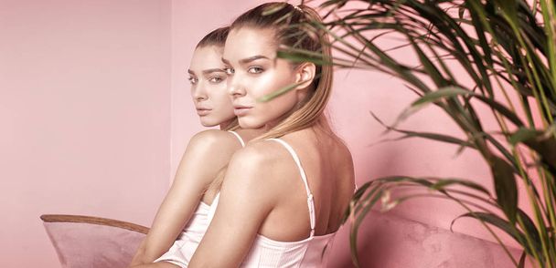 Beautiful caucasian twins female models on pink background. - Photo, image