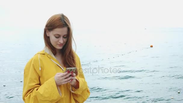 Žena hledá něco do telefonu na pobřeží moře. - Záběry, video