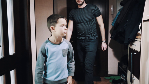 Little boy talks to long haired father in apartment hallway - Felvétel, videó