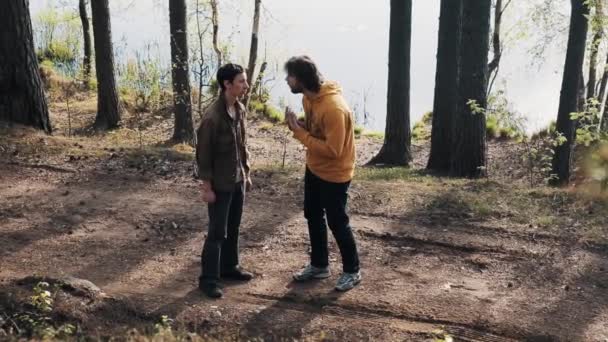 Dos amigos varones de pie en el sendero del bosque y peleas en el día soleado
 - Metraje, vídeo