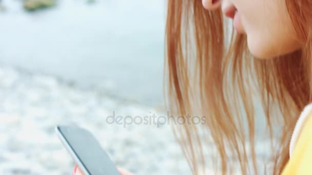 Femme regardant quelque chose au téléphone sur la côte de la mer
. - Séquence, vidéo