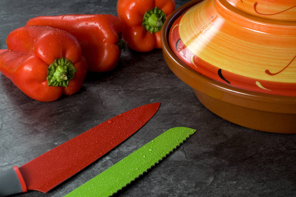 Cuchillos de colores, pimientos rojos y tajina de cerámica
 - Foto, imagen