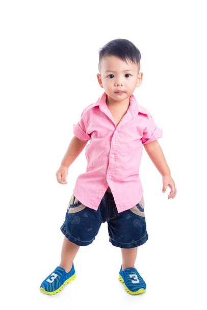 Маленький мальчик в розовой рубашке стоит на белом фоне
 - Фото, изображение