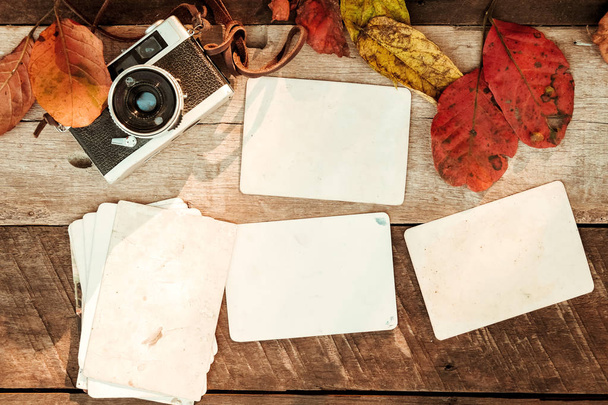 anlık kağıt fotoğraf albümü ile ahşap masa üzerinde sonbahar yaprakları - Fotoğraf, Görsel