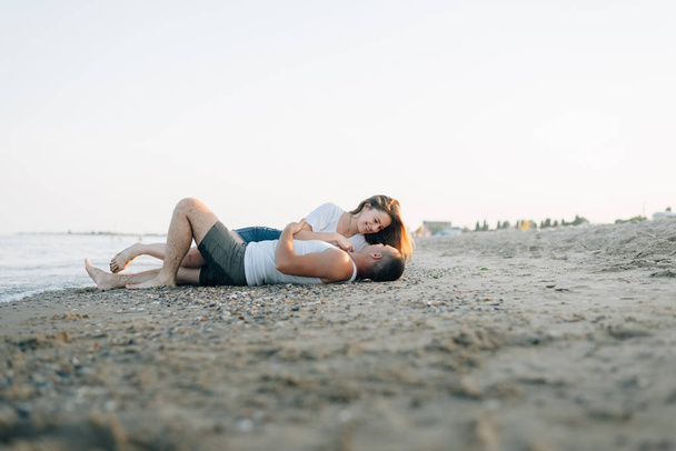 La pareja cariñosa con una sonrisa yace en la orilla del mar
 - Foto, imagen