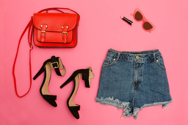 Jeanshosen, Schuhe und eine rote Handtasche, leuchtend rosa Hintergrund. Modisches Konzept - Foto, Bild