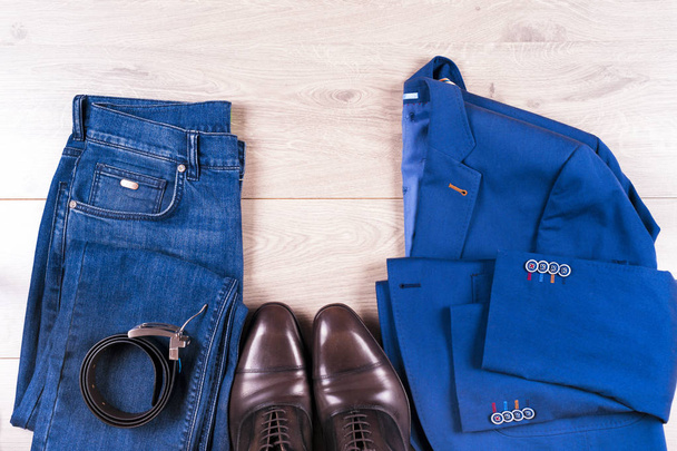 flache Lagegarnitur klassischer Herrenbekleidung wie blauer Anzug, Hemden, braune Schuhe, Gürtel und Krawatte auf Holzgrund. - Foto, Bild