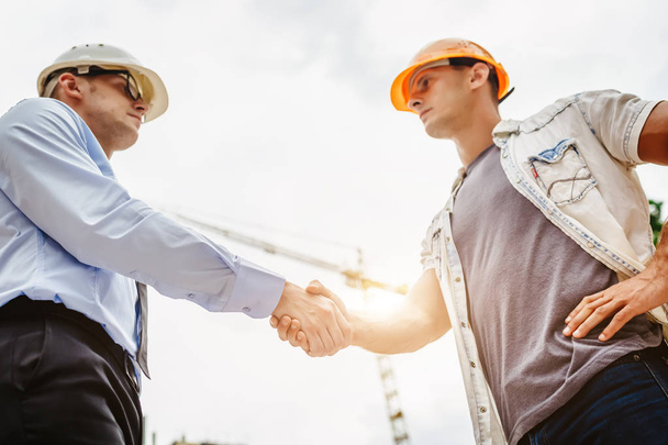 Architect engineer shaking hands other hand at construction site.  Business teamwork, cooperation, success collaboration concept - Photo, Image