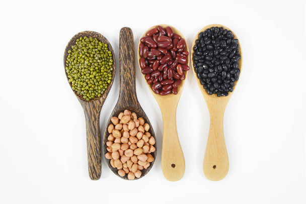 Sementes de feijão (feijão preto, feijão vermelho, amendoim e feijão Mung) útil para a saúde em colheres de madeira no fundo branco
. - Foto, Imagem