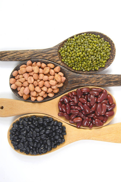 Σπόροι φασόλια (μαύρα φασόλια, κόκκινα φασόλια, φυστίκι και Mung Bean), χρήσιμο για την υγεία σε ξύλινα κουτάλια σε λευκό φόντο. - Φωτογραφία, εικόνα