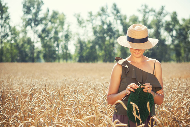 νεαρή γυναίκα που κεντά στο πεδίο σιτάρι - Φωτογραφία, εικόνα